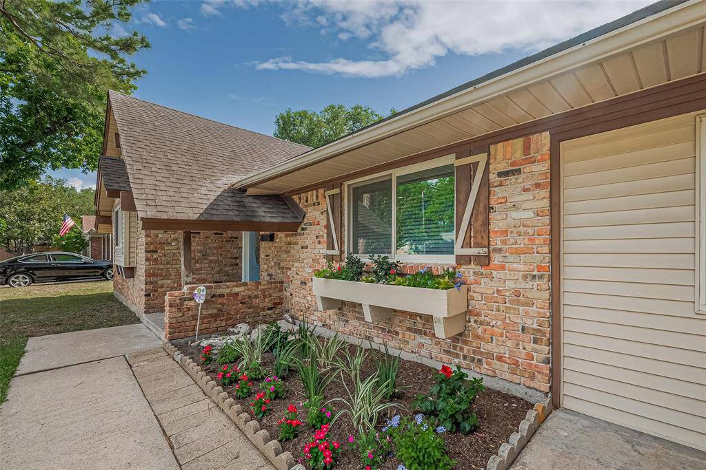 well-maintained flower beds. The driveway leads to a welcoming entrance, and mature trees enhance the curb appeal.