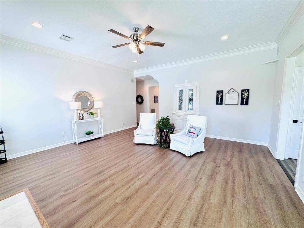 The LVP wood flooring was just installed, ceiling fan with light and recessed lighting illuminate the space! Other updates include the fireplace surround, and interior paint! Notice the elegant crown molding! There is also a wet bar with doors to close for privacy!