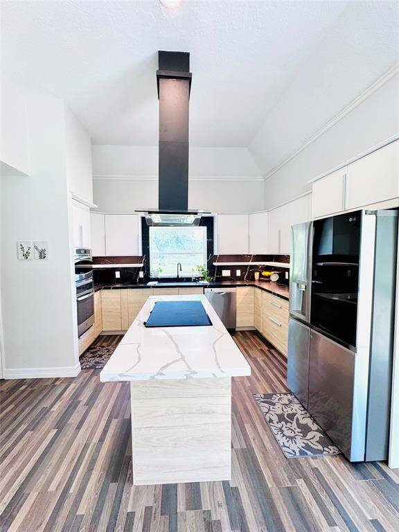 This kitchen has been completely redone! The lighting, the custom vent hood, the induction cooktop island with the quartz counters and the stainless appliances make prep and cooking (and clean up) a dream!