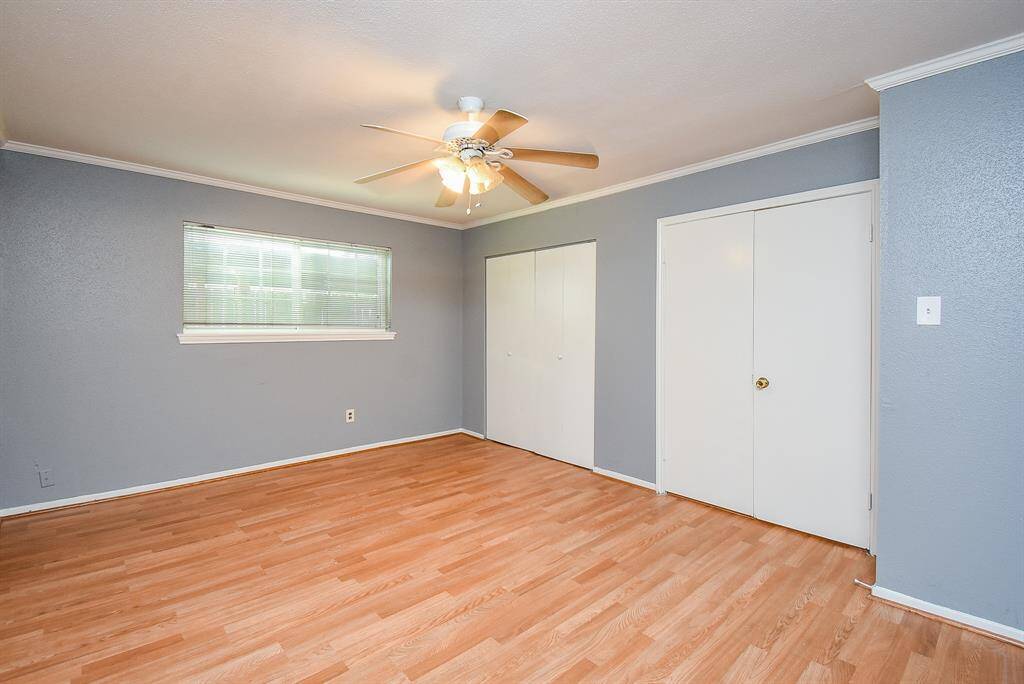 Cozy secondary bedroom with warm wood flooring, ample natural light, and a convenient closet.
