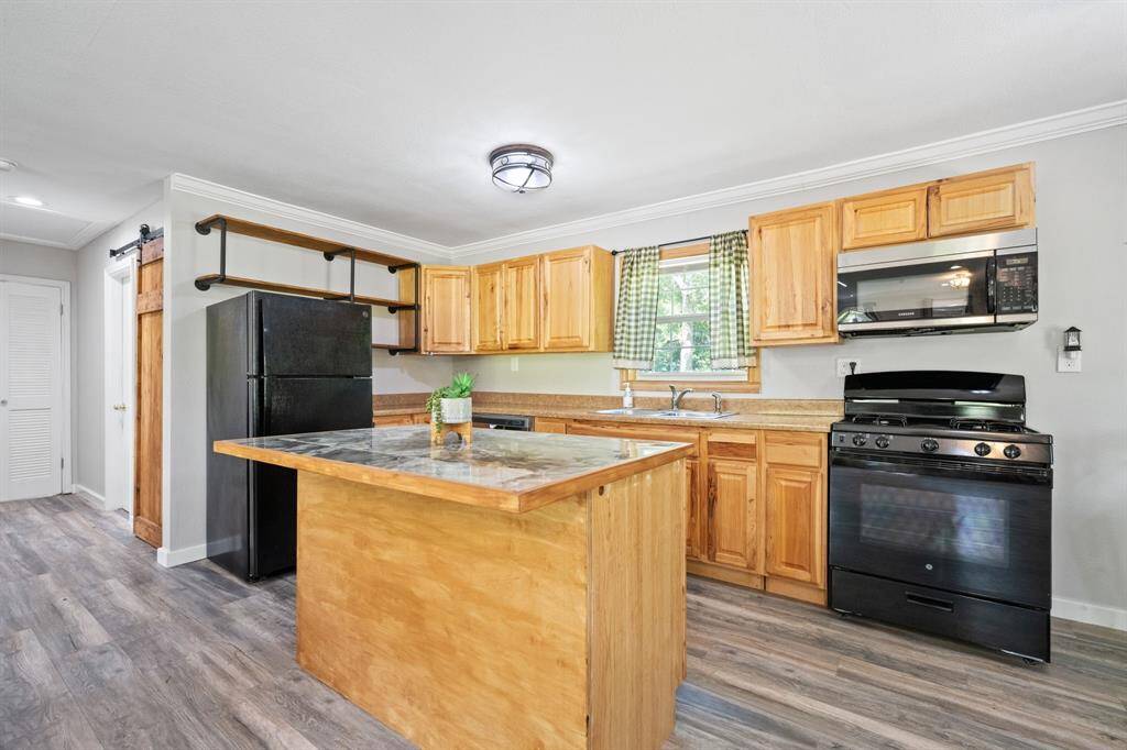 This kitchen has a gas stove, an island, brand new gorgeous cabinetry with soft close, a dishwasher, and microwave.