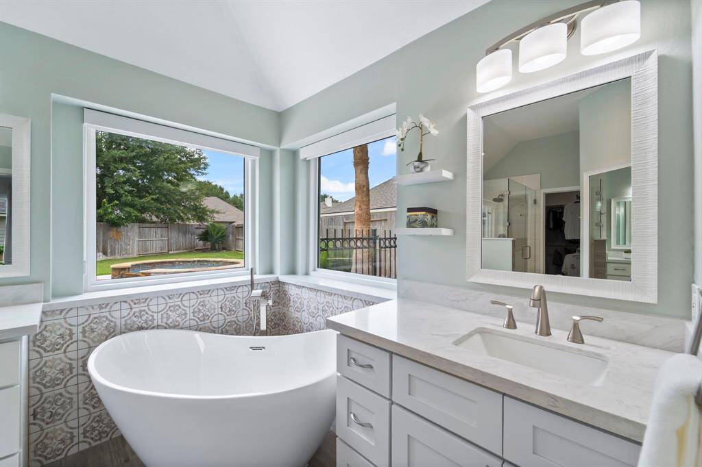 Primary bathroom remodeled 2024, complete with stand alone soaking tub under large windows to allow natural light inside.