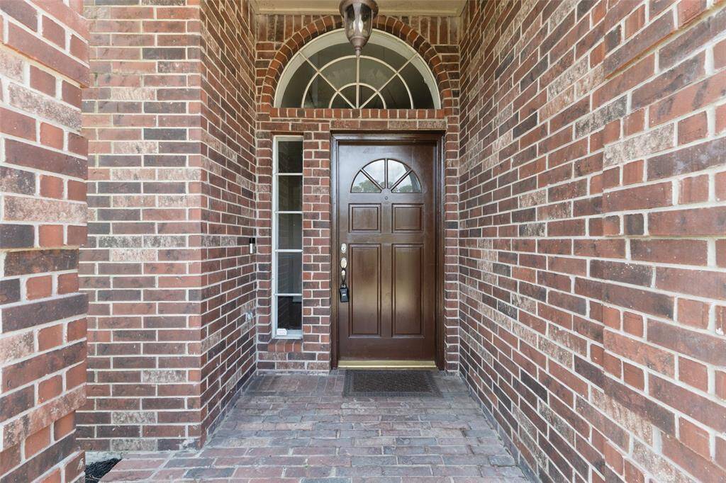 The charming covered front entry welcomes you with a timeless brick surround, offering both curb appeal and a warm, inviting atmosphere.