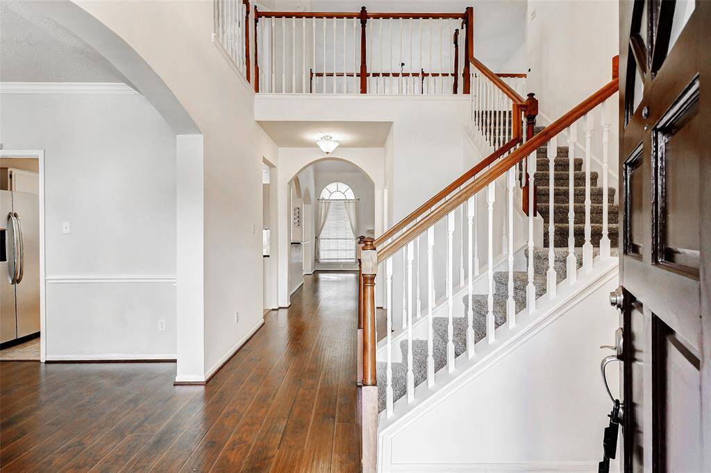 Step into a soaring entryway that sets the tone with its sense of space and light, featuring gleaming laminate wood floors that flow seamlessly throughout the formal dining room and family room.