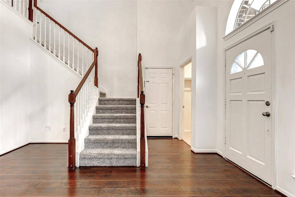 The entryway is flooded with natural light, thanks to a sidelight window and an elegant sunburst window overhead, creating a warm and inviting first impression.