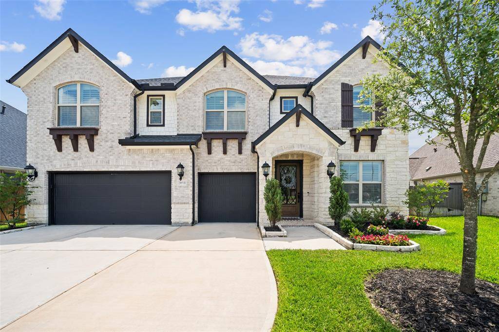 French Country elevation featuring recessed lighting under the eaves, 4 designer coach lamps, and wood architectural accents under the second story windows.