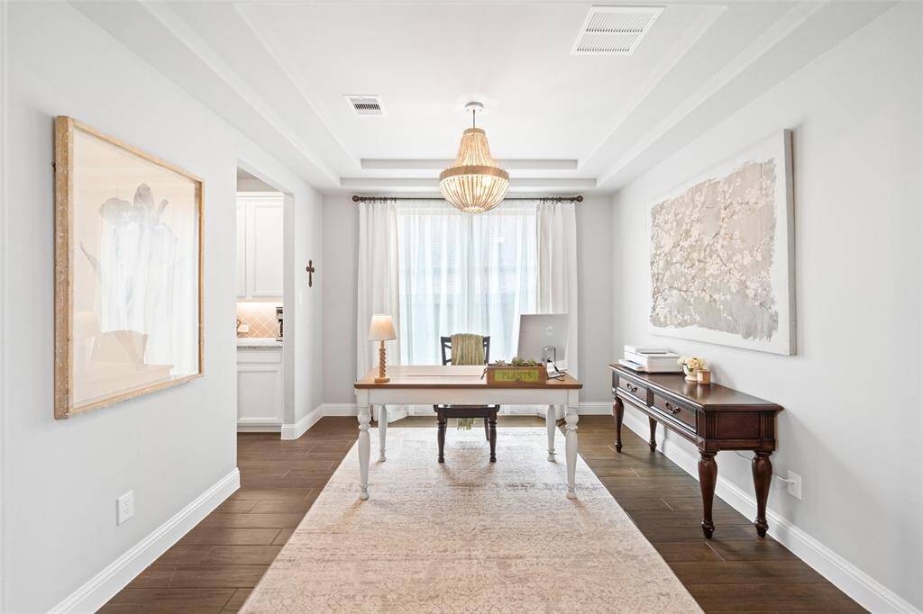 Dining room currently being used as a secondary home office space with designer chandelier and huge picture window has passage to the kitchen while being open to the foyer.