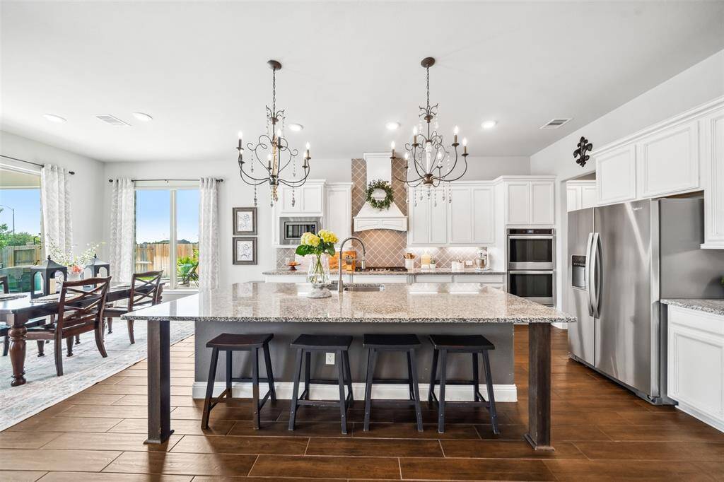 Gorgeous kitchen with stunning French chandeliers over a huge center island and designer range hood includes a 36" 5-burner cooktop and double wall ovens.