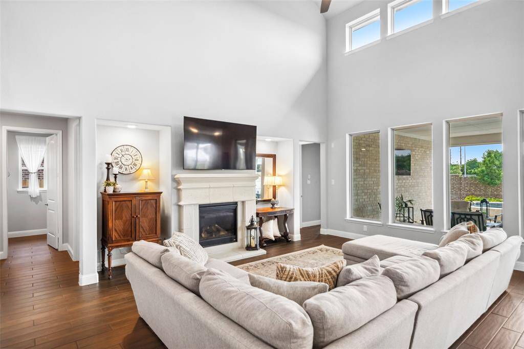 Main living room with 19 ft. ceilings, views to the patio and pool includes a gas fireplace with elegant cast-stone surround and niches with recessed art lighting. Room includes an in-floor electrical outlet for room-center power needs.
