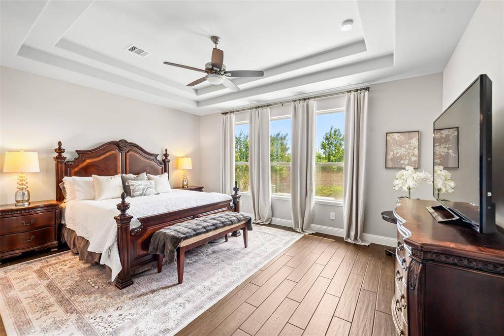 Primary bedroom looks out to gorgeous landscaping and features a double-tray ceiling, remote-controlled light and ceiling fan, and USB electrical outlets on each side of the bed.