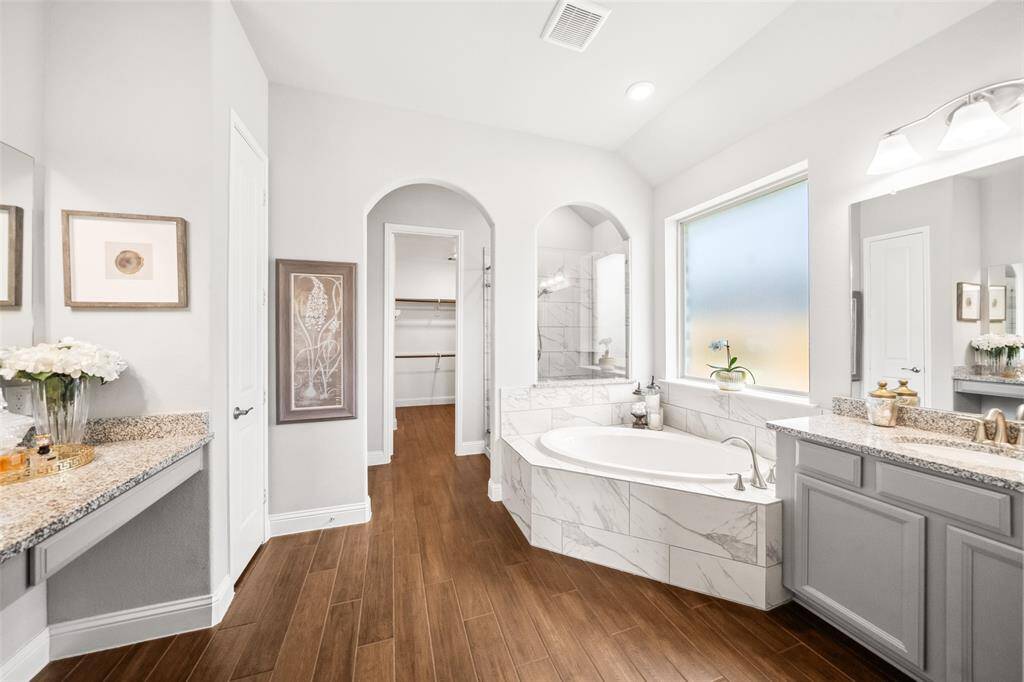 Spacious primary bath with double sinks and separate vanities, soaking tub, and large tile-floored shower with shower seat. Bath closet to the left with water closet adjacent.