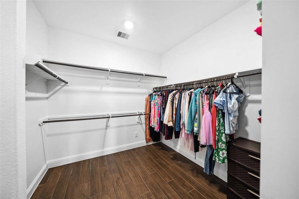 Larger side of the L-shaped primary walk-in closet. Smaller side not shown is to the left and includes a taller single rod wall as well as a double-hanger wall.