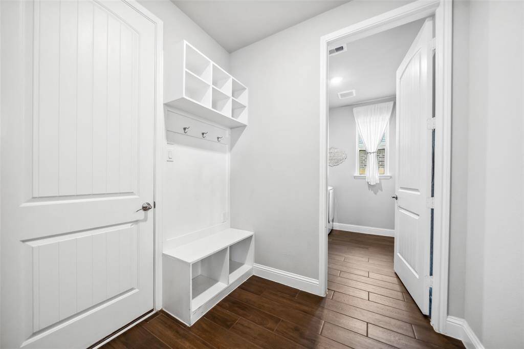 Mudroom with built-in bench with hooks and cubbies is flanked by the laundry room, half-bathroom, and a grand under-the-stairs storage room.