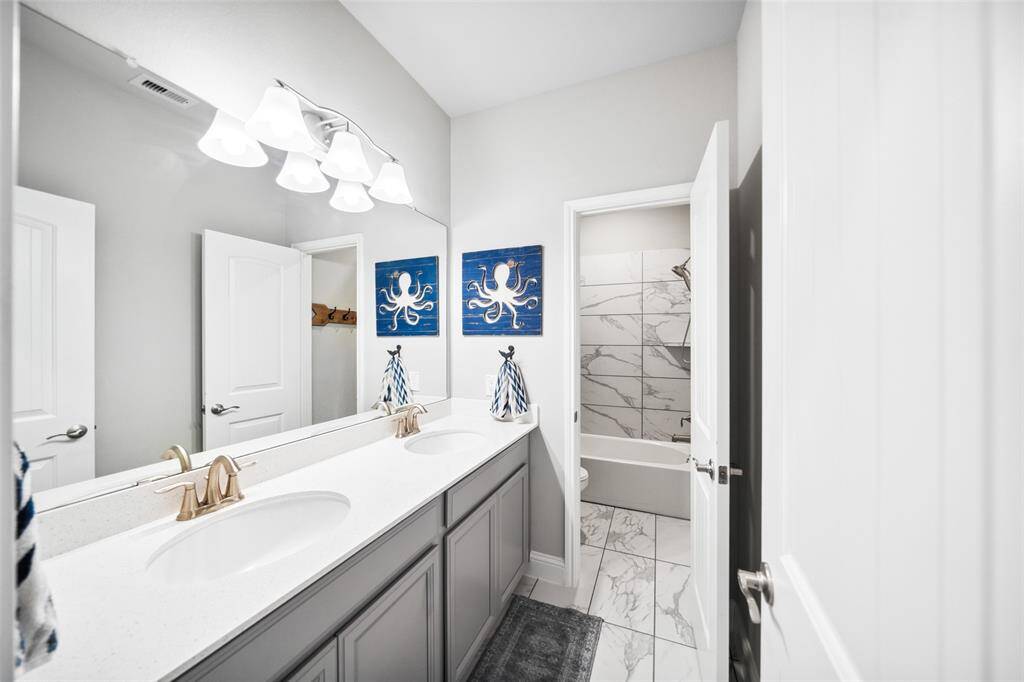 Secondary bath with double-sink vanity. Toilet and shower separated for privacy.