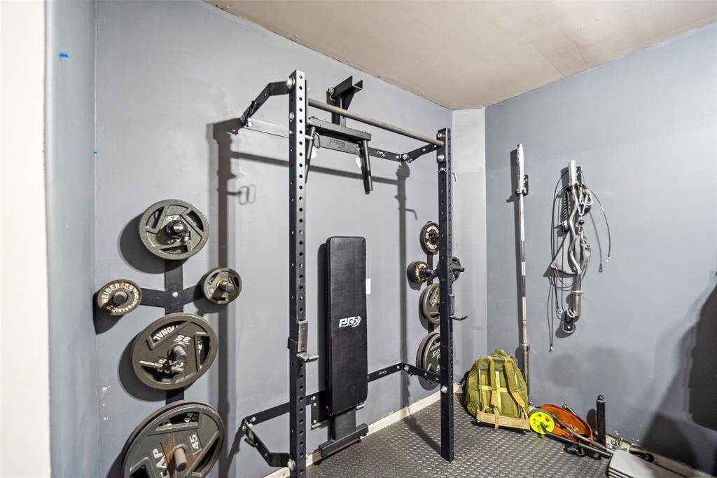 At the back of the single garage is this PRX fold-down workout weight bench, which stays with the house! The weights and accessories are not included, but when folded up as shown here, a car can still park inside the garage. There is a also a tv mount and electrical wall outlet on the adjacent wall so that you can add a tv for entainment while you workout!