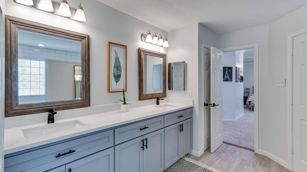 Renovated Master Bathroom with granite countertop, double vanity sinks and updated lighting.