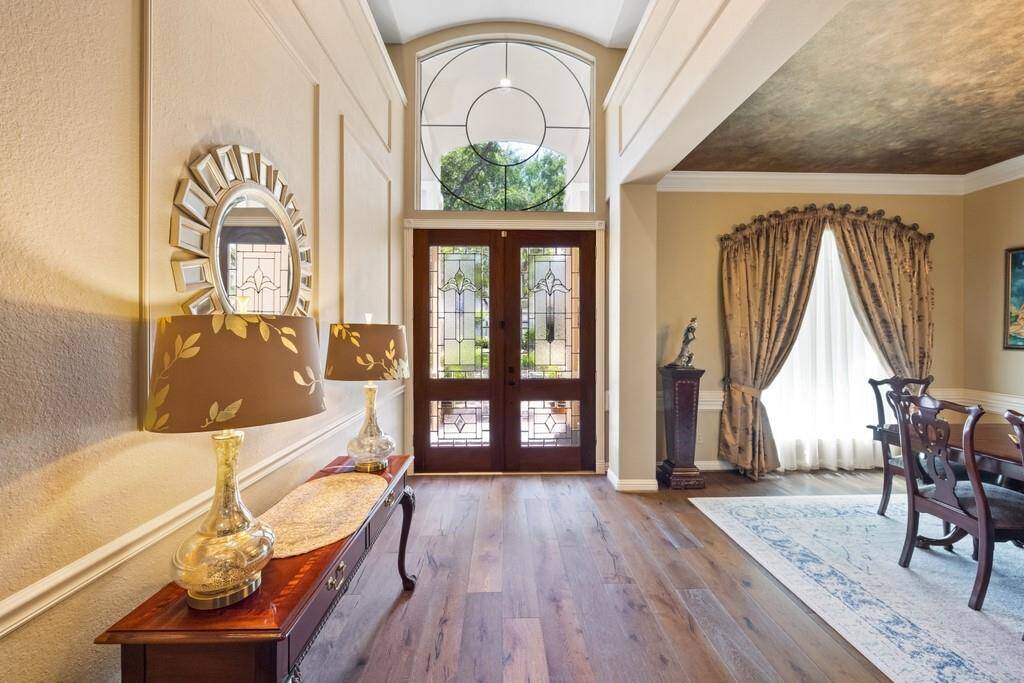 Bathe in natural light from the grand arched window above the front doors, while refined wall paneling adds a touch of timeless charm to this welcoming entryway.