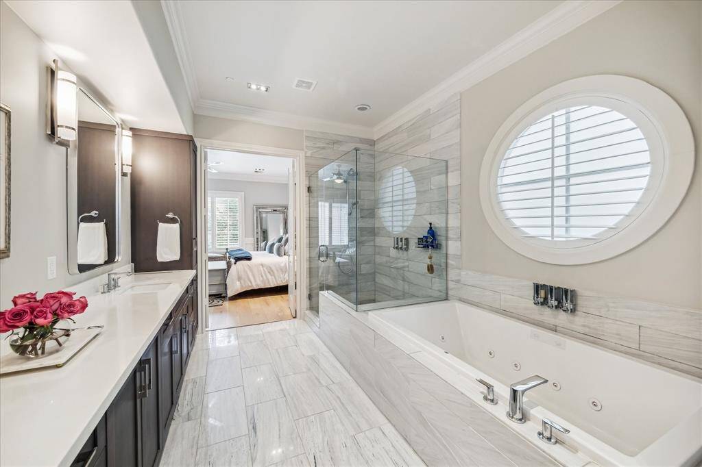 Striking white marble enhances both the floors and walls in this primary bathroom, adding timeless elegance and refined detail to the space.