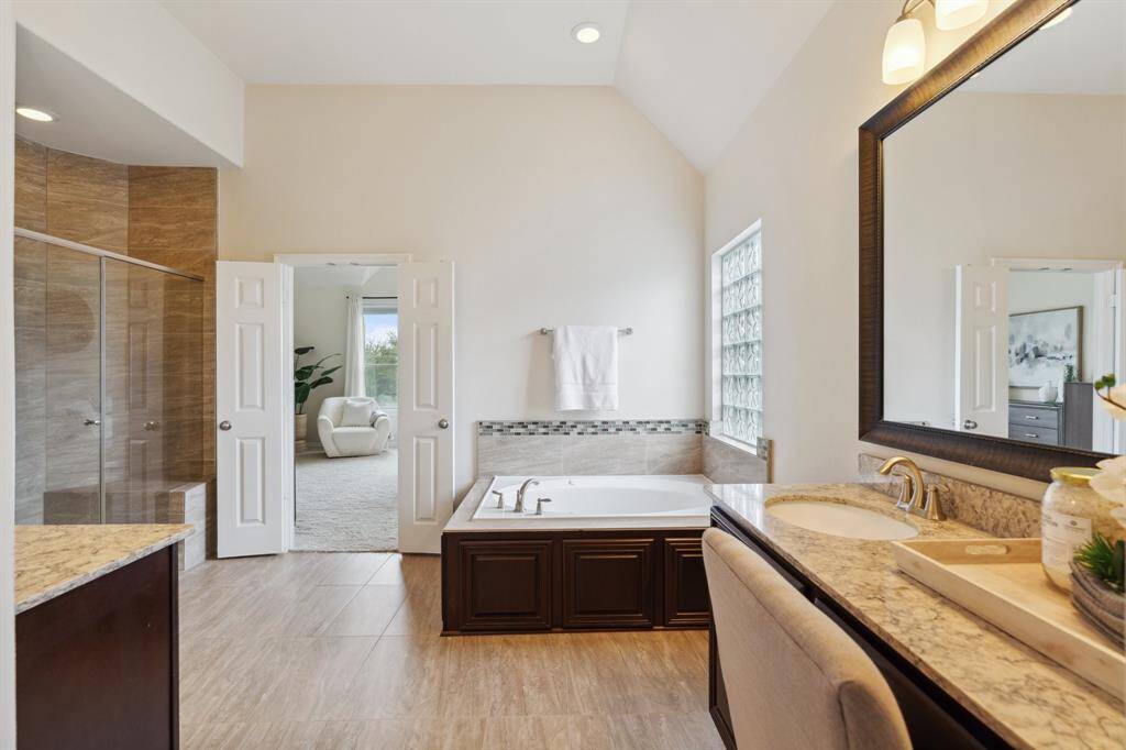 The ensuite bathroom with double sinks, separate vanities, walk in shower, and a luxurious jetted tub for ultimate relaxation.