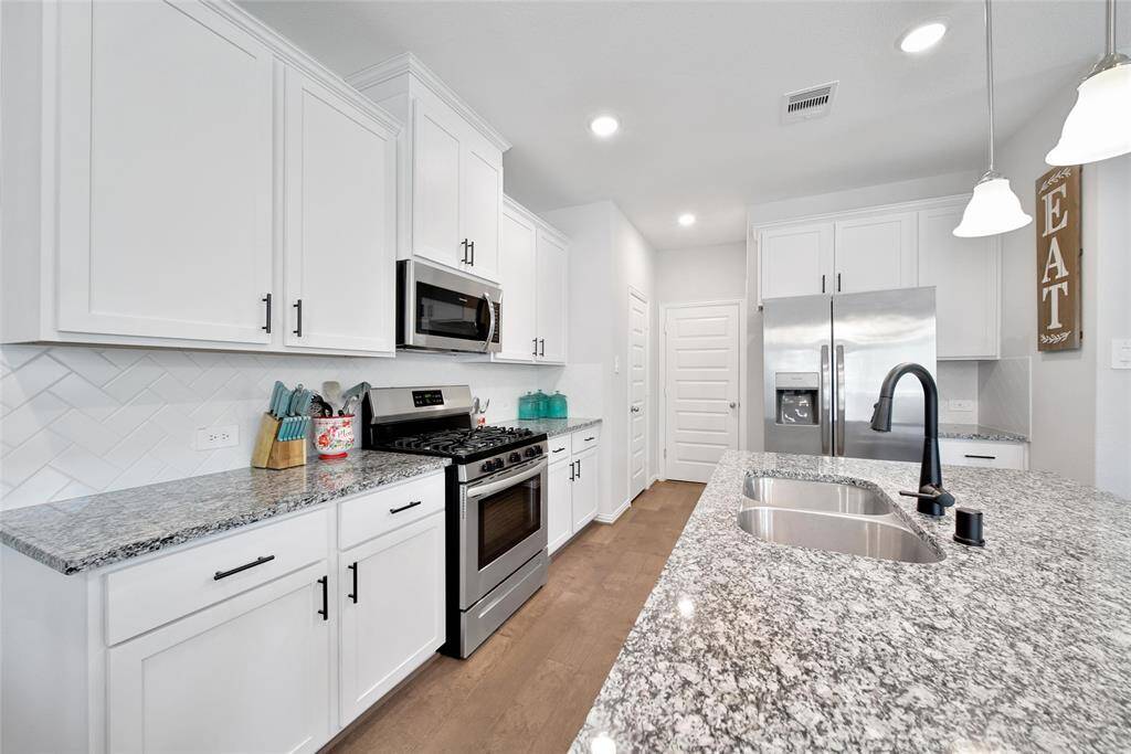 Granite countertops, recessed sink, abundance of cabinet space this kitchen has it all! Pantry and garage entry just past the refrigerator that conveys with the home.