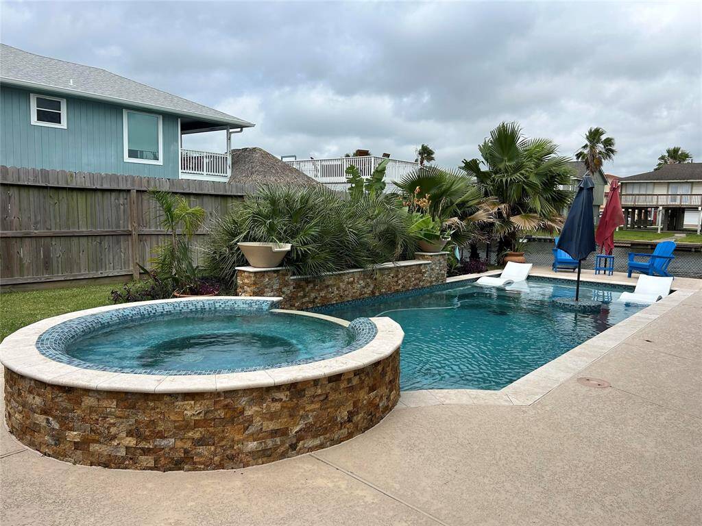 Large in ground gunite pool/spa with a tanning ledge, raised wall, and decorative lighting on the wall
