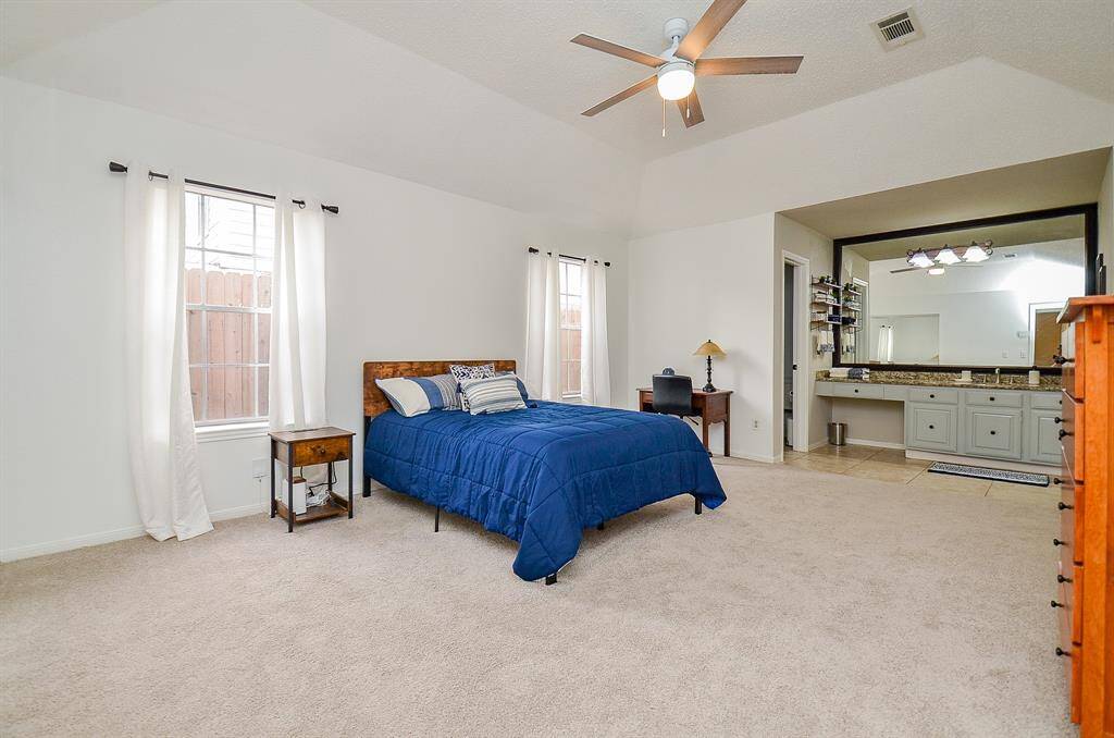 A generously sized retreat featuring high ceilings, plush carpeting, and an en-suite bath.