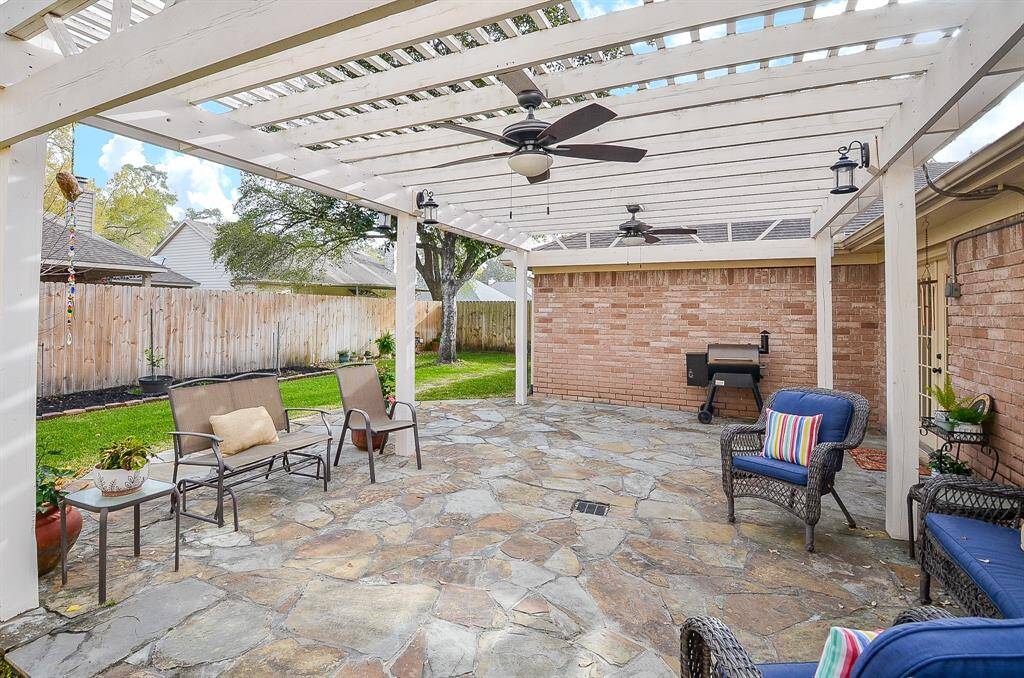 The expansive flagstone patio with ceiling fans and string lighting creates a relaxing ambiance.