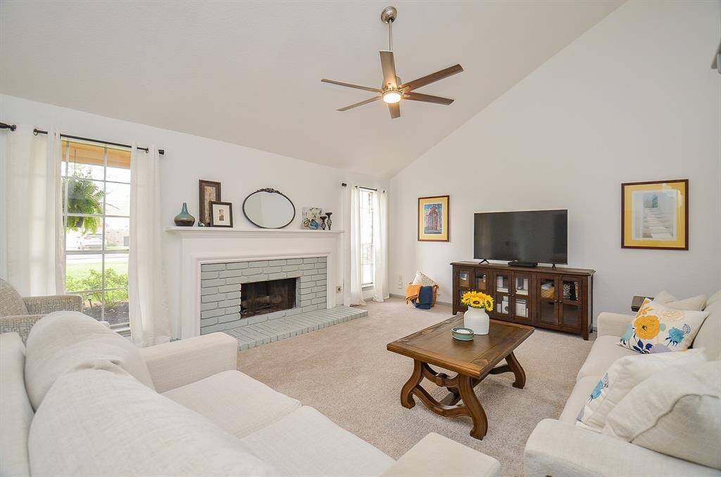 Step into this inviting living room featuring soaring vaulted ceilings, a cozy fireplace, and abundant natural light.