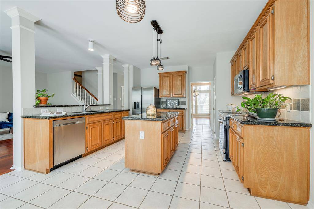 Gorgeous kitchen offers tile floors, tile backsplash, granite counter tops, granite island workspace, new electric cooker, new SS built-in microwave, walk-in pantry, opens to the breakfast room.