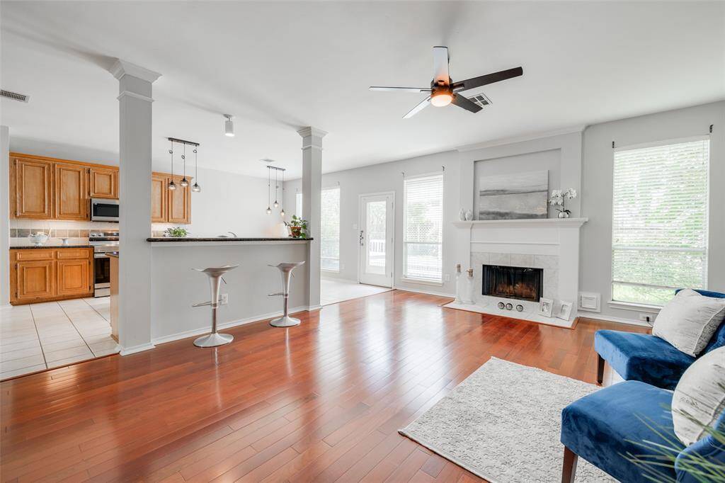 Living room featuring a new black modern ceiling fan with light fixture, tiled gas wood burning fireplace, enjoy entertaining with friends at the breakfast bar open to the kitchen.
