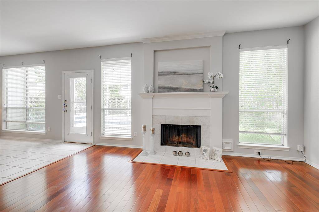 Living room with laminate floors, featuring a new black modern ceiling fan with light fixture, tiled gas wood burning fireplace, enjoy entertaining with friends at the breakfast bar open to the kitchen.
