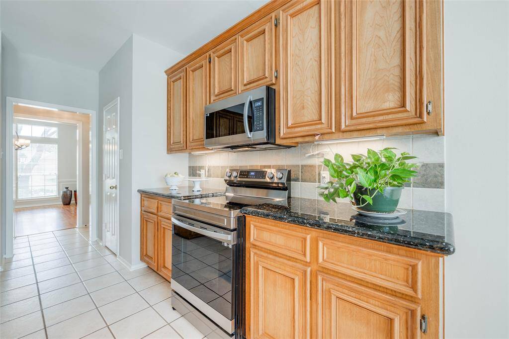 Gorgeous kitchen offers tile floors, tile backsplash, granite counter tops, granite island workspace, new electric cooker, new SS built-in microwave, walk-in pantry, opens to the breakfast room.