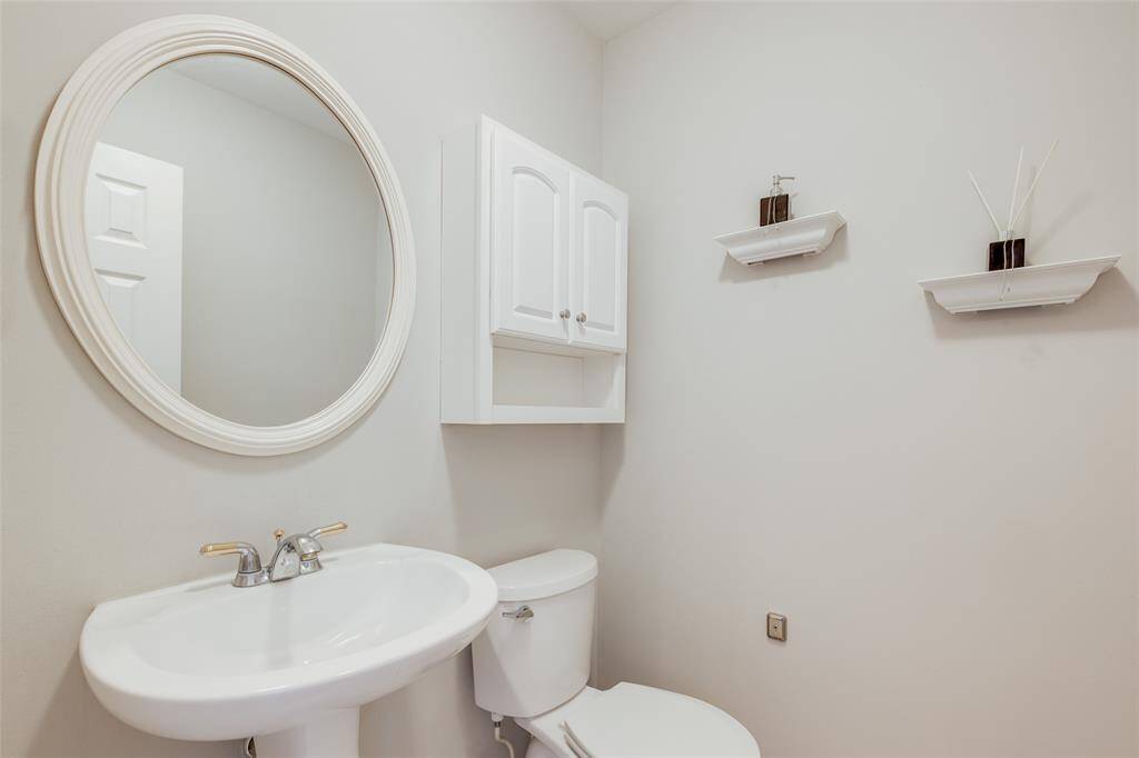 Half bath with pedestal sink, storage cabinet, circular mirror