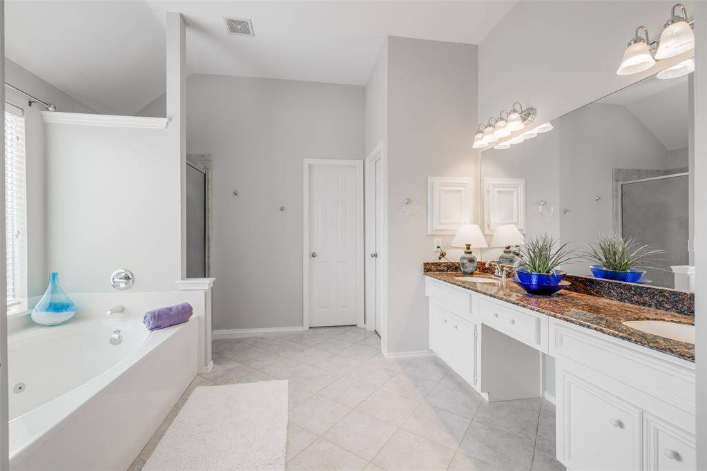Primary bath offering tile floors, double sinks, vanity area, jetted tub, separate shower &  a double walk-in closet.