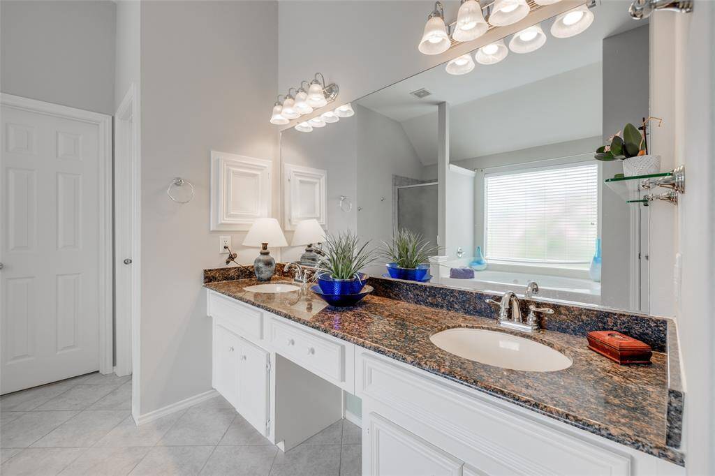 Primary bath offering tile floors, double sinks, vanity area, jetted tub, separate shower &  a double walk-in closet.