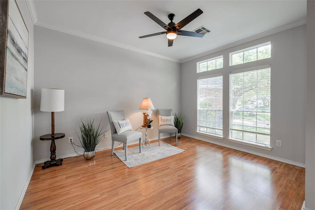 Study with hardwood laminate floors, crown molding & new black ceiling fan with light fixture.
