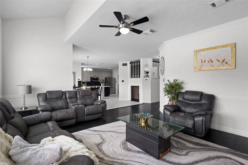This spacious living room features vinyl plank flooring opens into dining area and kitchen, creating a seamless flow. Elegant decor and natural light enhance the inviting atmosphere.