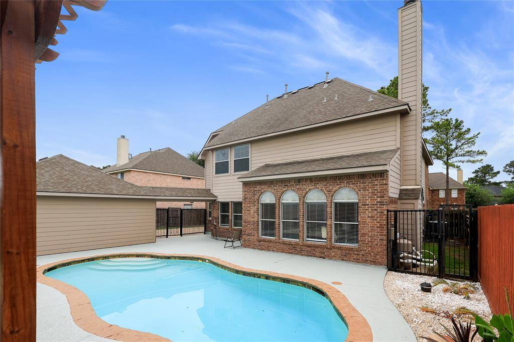 Charming two-story brick house with a fenced backyard featuring a saltwater swimming pool. The large windows and well-maintained exterior create an inviting atmosphere, perfect for relaxation and entertainment.