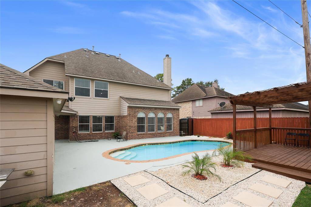 This spacious backyard features a modern two-story home with a private saltwater pool and a cozy covered pergola/wooden deck, perfect for outdoor relaxation and entertaining.