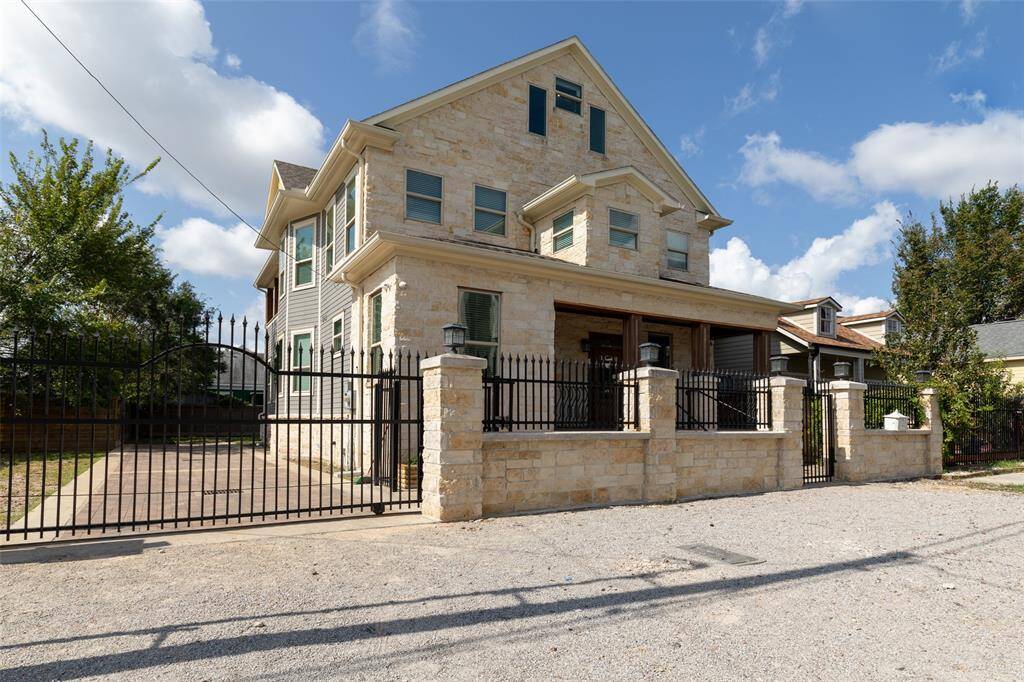 1509 Summer St is a two-story home featuring a covered front porch with wooden columns, surrounded by a wrought iron fence with gated entry, offering both privacy and curb appeal.