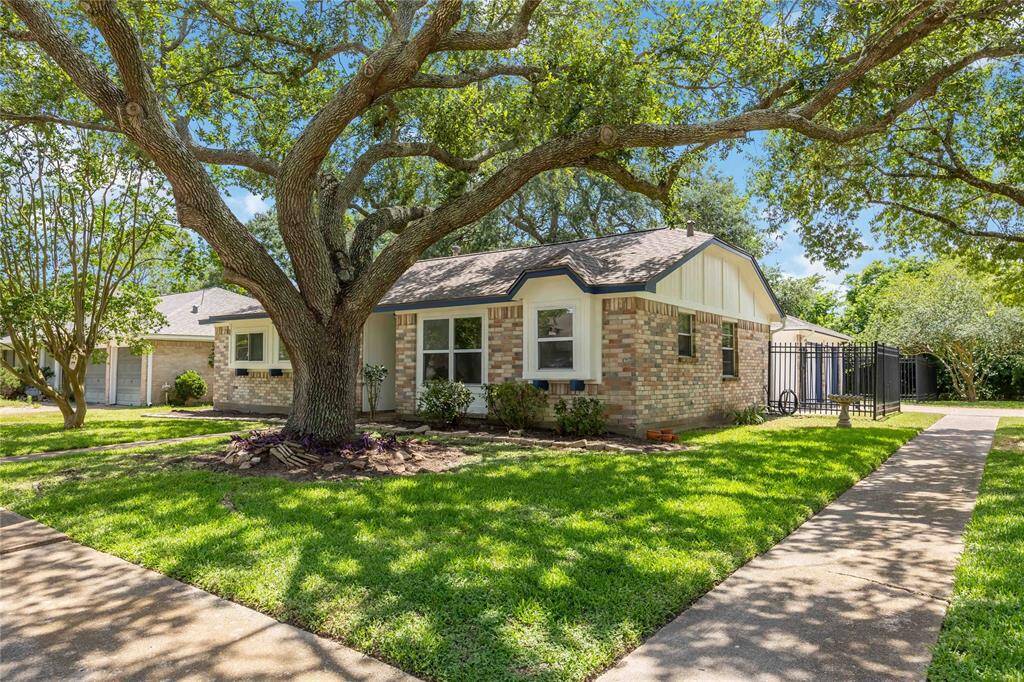 Charming brick home with a classic design, set amidst lush greenery and mature trees. The spacious front yard features a well-maintained lawn and a wide pathway leading to the entrance. Perfect for those seeking a cozy and inviting neighborhood setting.