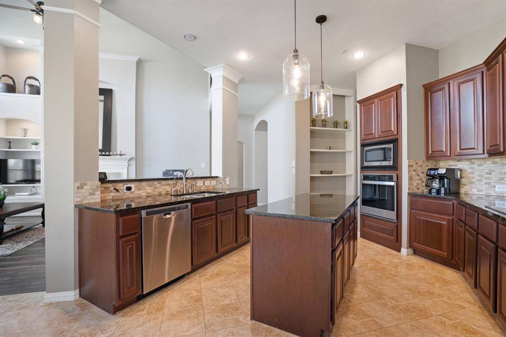 Kitchen area has all your essentials: island for prepping meals, stainless steel appliances, shelving for your cookbooks and decor with many cabinets for storage.
