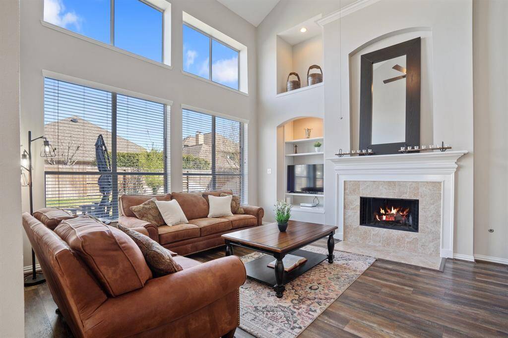 Family room off the back of the home with high ceilings, large windows, built-in tv nook, and a cozy fireplace.