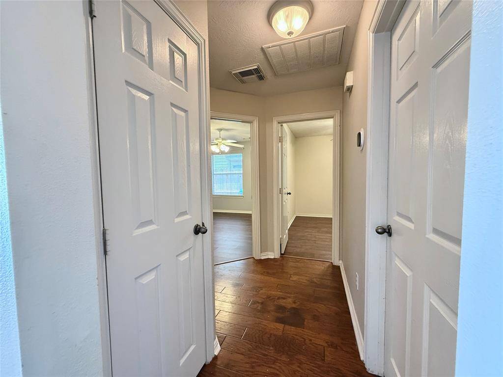 Located in the front part of the home, this hallway leads to the utility room, garage, two bedrooms, and a secondary bath.
