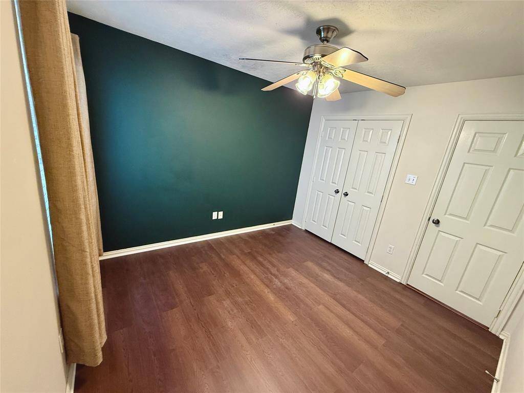 Secondary bedroom includes an accent wall, ceiling fan, and ample closet space.