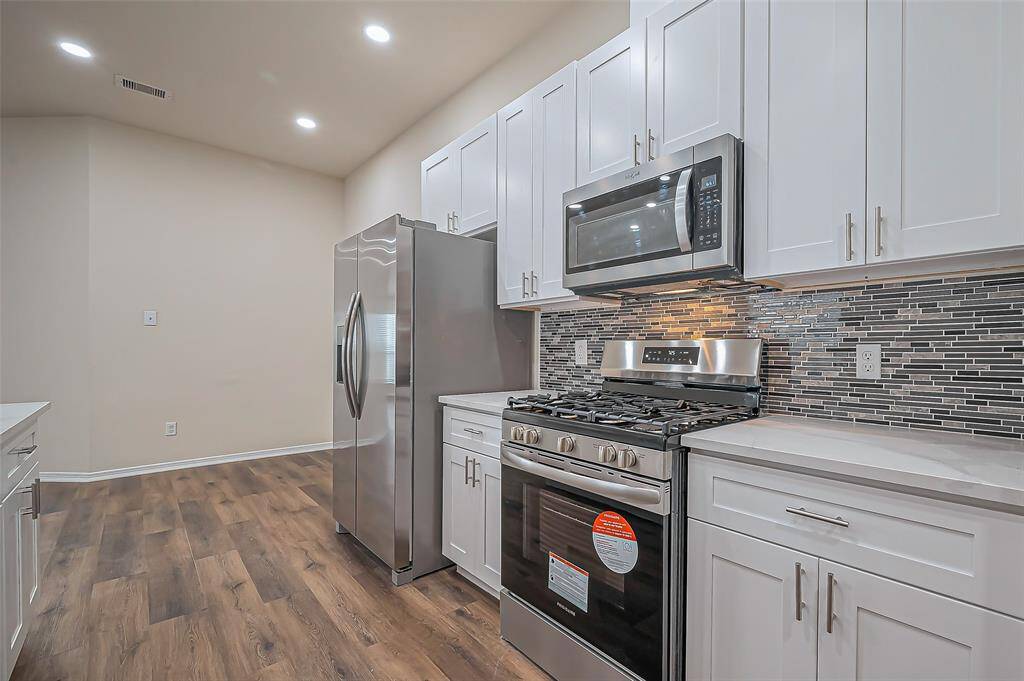 On the opposite side of the kitchen, you'll find a gas range, microwave, and refrigerator, all brand new (2024). Shaker cabinets with adjustable shelves offers customizable storage options, perfect for organizing kitchen essentials and maximizing space.