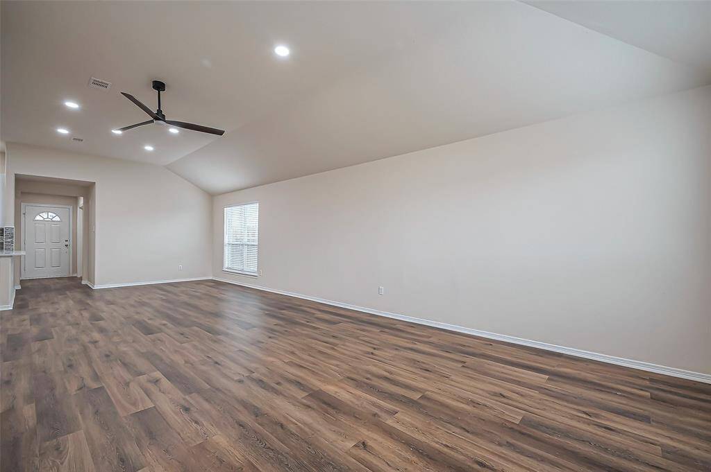 A large window at the far end of the family room overlooks the side yard, adding natural light to the space. This area would make a great formal dining room if desired. The room offers ample wall space for furniture placement, and the high ceiling enhances the open feel. A ceiling fan (2024) is centrally located, ensuring comfort in this expansive family room.