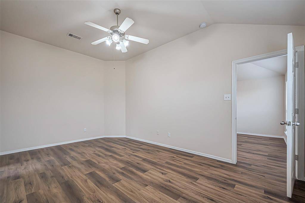 A door from the family room leads into the owner's suite, a private retreat at the rear of the home. The room features high ceilings with a ceiling fan (2024) for added comfort. The continuous LVP flooring creates a warm and inviting atmosphere, making this space perfect for relaxation.