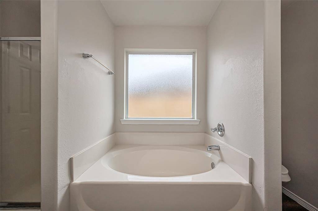 The owner's suite features a relaxing garden soaking tub paired with a frosted window for privacy and natural light. This home was built with durable PEX plumbing throughout, with a PEX manifold panel located in the garage. This panel allows for easy water control, making it simple to shut off or adjust water flow to individual fixtures as needed.