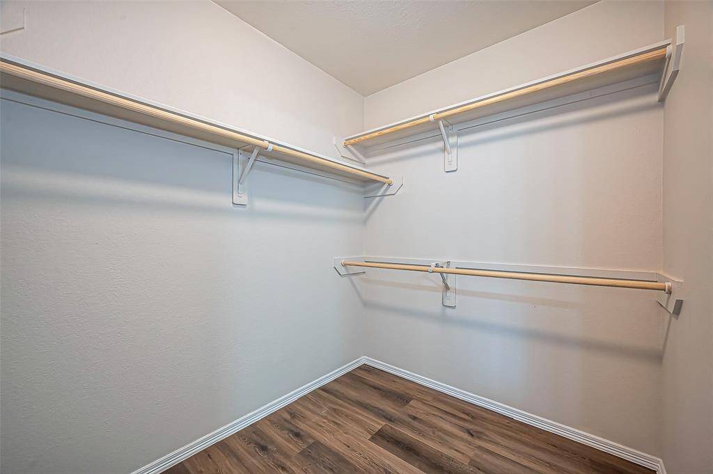 The owner's spacious walk-in closet measures 7.11 x 6.2 and is well-lit for convenience. Double rods on each side maximize hanging space, while a long single rod along the back provides additional storage. This thoughtfully designed layout offers plenty of room for organization.